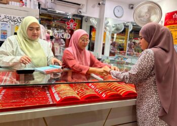 SEORANG pelanggan mencuba rantai tangan yang dijual di sebuah kedai emas di Pasar Siti Khadijah, Kota Bharu, Kelantan. – UTUSAN/ ROSLIZA MOHAMED